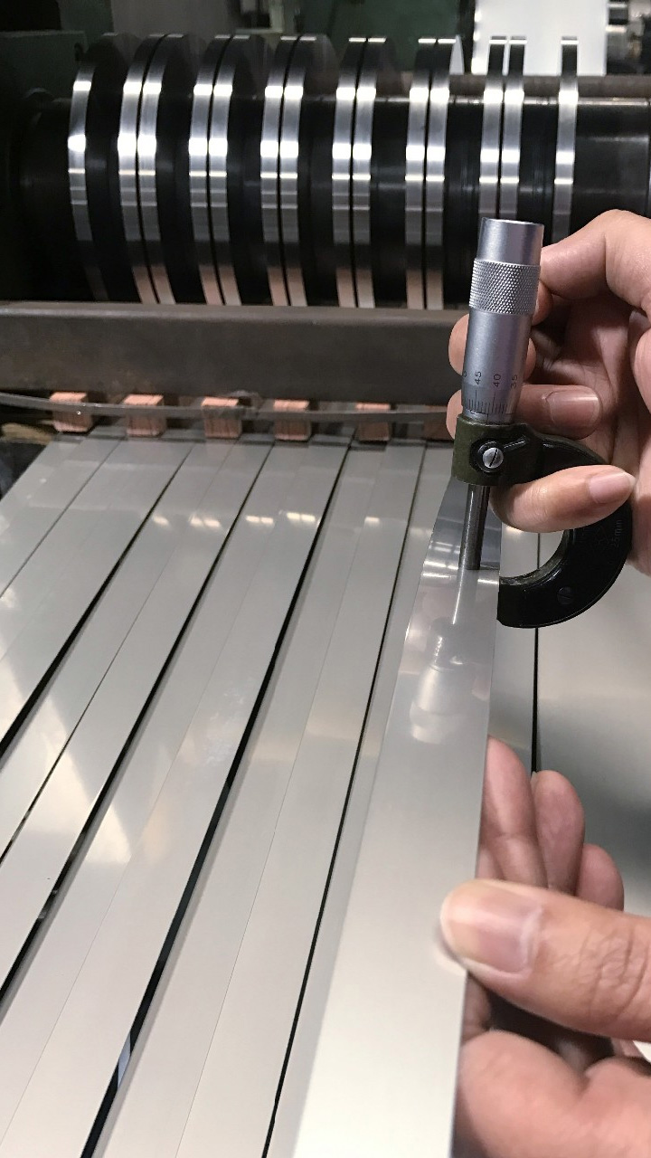 Operator checking slit strip thickness with a micrometer at the slitting line
