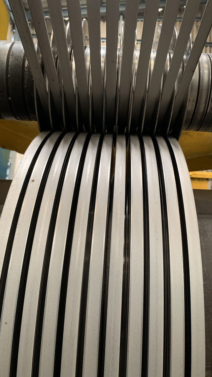 Close-up of slit stainless steel strips passing through the separator on the slitting line